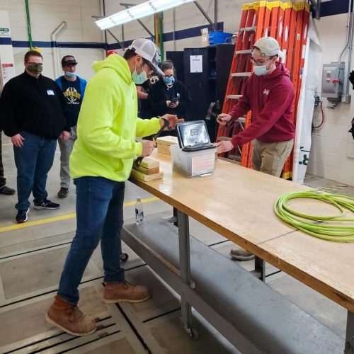 Ryan and Carter race to perform common building tasks for a group of students interested in trades.